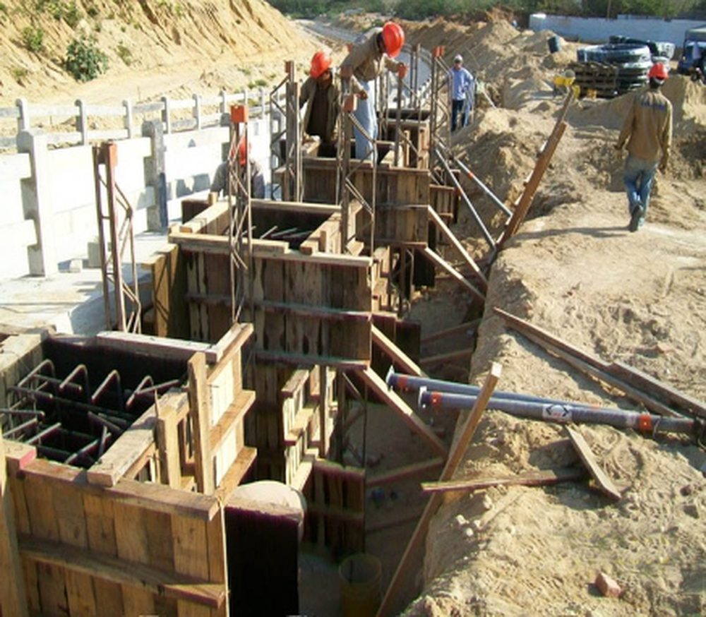 Encofrado y armadura de cimentación en zanja, con personal en obra